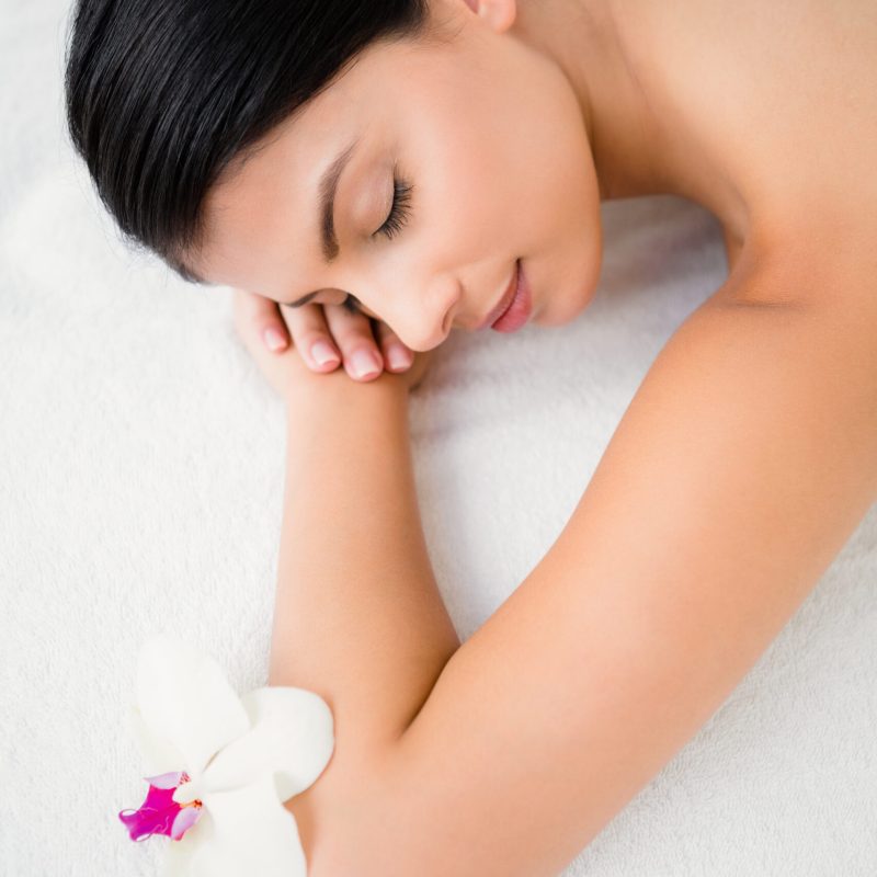 Pretty brunette enjoying a massage with flower at health spa Pretty brunette enjoying a massage with flower at health spa
